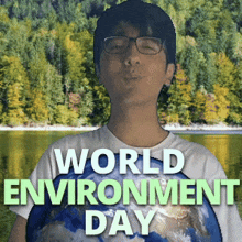 a man wearing glasses holds a globe in front of a lake with the words world environment day below him
