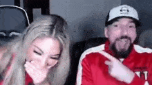 a man and a woman are laughing together while sitting next to each other .