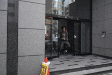 a man in a plaid shirt is standing in front of a building that has the letter a on it