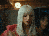 a woman with blonde hair and red lips is standing in front of a mirror