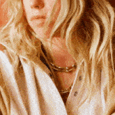a close up of a woman 's face wearing a necklace and a jacket .