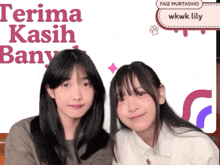 two girls are standing next to each other in front of a banner that says terima kasih bany