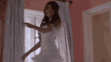 a woman in a wedding dress is standing in front of a window .