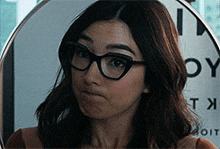 a woman wearing glasses is standing in front of a sign that says oy