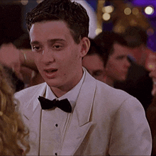 a man in a white tuxedo and bow tie