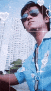 a man wearing sunglasses and a blue shirt stands in front of a skyscraper