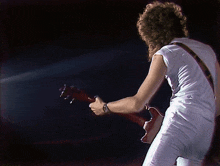 a man is playing a guitar in a dark room