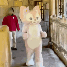 a stuffed animal in a cat costume is walking down a hallway next to a man in a red shirt .