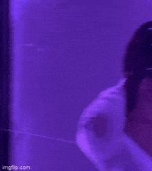 a blurry picture of a woman standing in front of a window with purple lights .