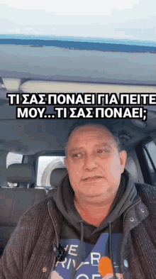 a man is sitting in the back seat of a car with a microphone in his mouth .