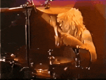 a man playing drums in a dark room with a purple background