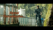 a man riding a bike with the words " ilimai thirumbuthe " written above him