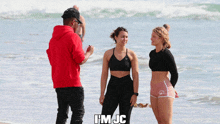a man in a red hoodie stands next to two women on a beach and says i 'm jc on the bottom