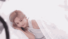 a woman in a white dress is laying on a bed with a white curtain behind her