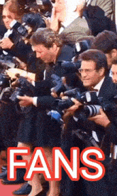 a group of people are taking pictures and the word fans is visible