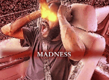 a man with a beard is sitting in a chair with the word madness on the bottom right