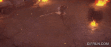 a man in armor is standing in front of a fire .