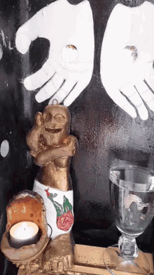 a statue of a woman with a candle in front of a painting of hands