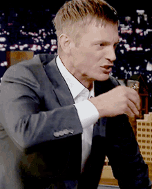 a man in a suit and white shirt is holding a lighter