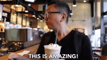 a man is drinking a milkshake in a starbucks and says this is amazing .