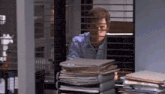 a man looking out a window with a stack of papers