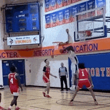 a basketball game is being played in a gym with a scoreboard .