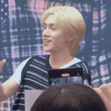 a man with blonde hair is smiling and holding a phone