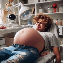 a man is laying in a hospital bed with a very large pregnant belly .