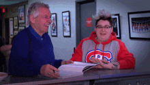 a woman wearing a montreal canadiens sweatshirt is signing a book