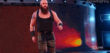 a man with a beard is standing in front of a braun strowman sign .