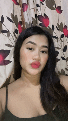 a woman taking a selfie in front of a curtain with flowers on it