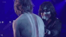a man without a shirt is singing into a microphone while another man holds his back .