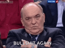 a man in a suit and tie is sitting in a row with his arms crossed and says `` bullshit again '' .