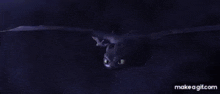 a toothless from how to train your dragon is flying through the air with a purple light coming out of its mouth .