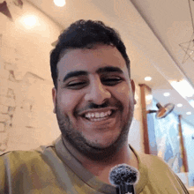a man with a beard is smiling and holding a microphone in his hand