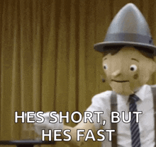 a wooden puppet in a suit and tie is holding a piece of paper and saying he 's short but he 's fast
