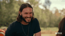 a man with long hair and a beard is smiling for a netflix ad