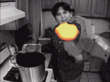 a black and white photo of a man in a kitchen with a pot