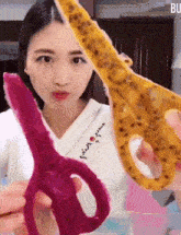 a woman in a white shirt is holding a pair of scissors with fruit on them .