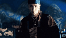 a young man wearing a headband and a necklace is standing in front of a blue wall .