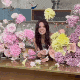 a woman sitting in front of a bunch of flowers