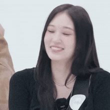 a woman with long black hair is smiling and wearing a name tag that says ' a ' on it