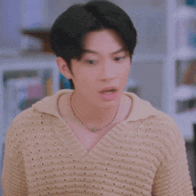 a blurry picture of a man wearing a tan sweater and a necklace