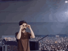 a man is wearing a fake mustache and glasses in front of a crowd .