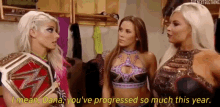 three female wrestlers are standing next to each other in a locker room talking to each other .
