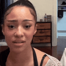 a woman with a bra on looks at the camera with a bottle of aquafina water in the background