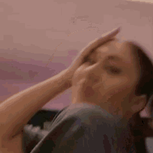 a woman is holding her hand to her forehead and looking at the camera .