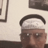 a man wearing a bandana on his head and glasses is sitting on a couch .