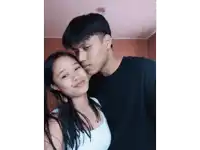 a man and a woman are posing for a picture and the woman is wearing a white tank top