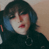 a woman with blue hair and red eyes is making a hand gesture .